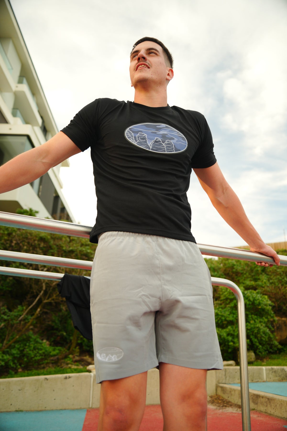 Model wearing the SistazT. Navy shirt and light grey Motion Shorts beside a railing.